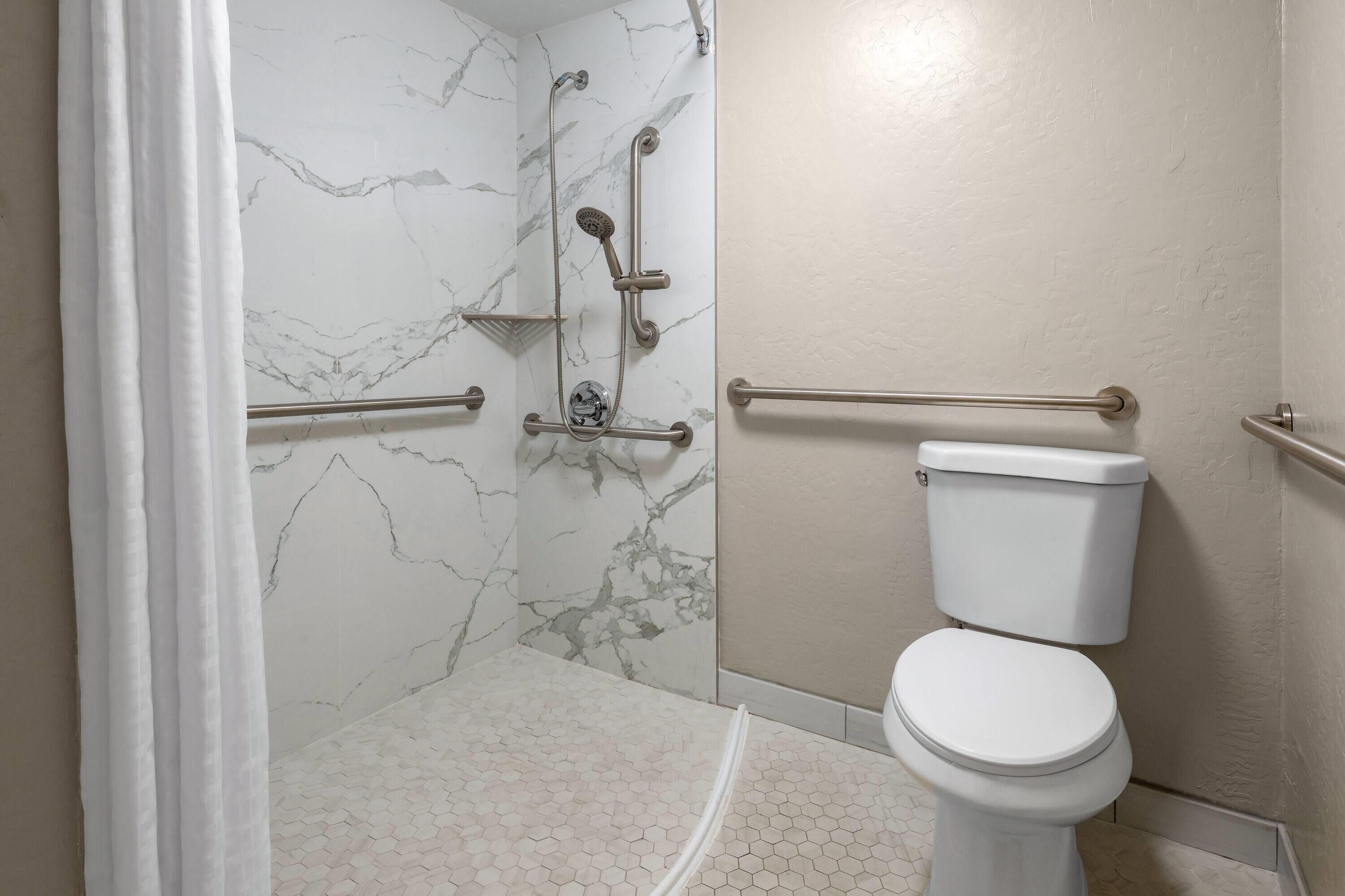 A bathroom with a shower, toilet, and marble walls.
