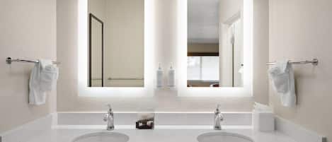 A bathroom with two sinks, a large mirror, and a hair dryer in the cabinet.