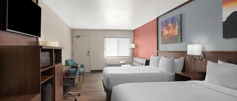 Habitación de hotel con dos camas, televisión, escritorio con silla y ventana.