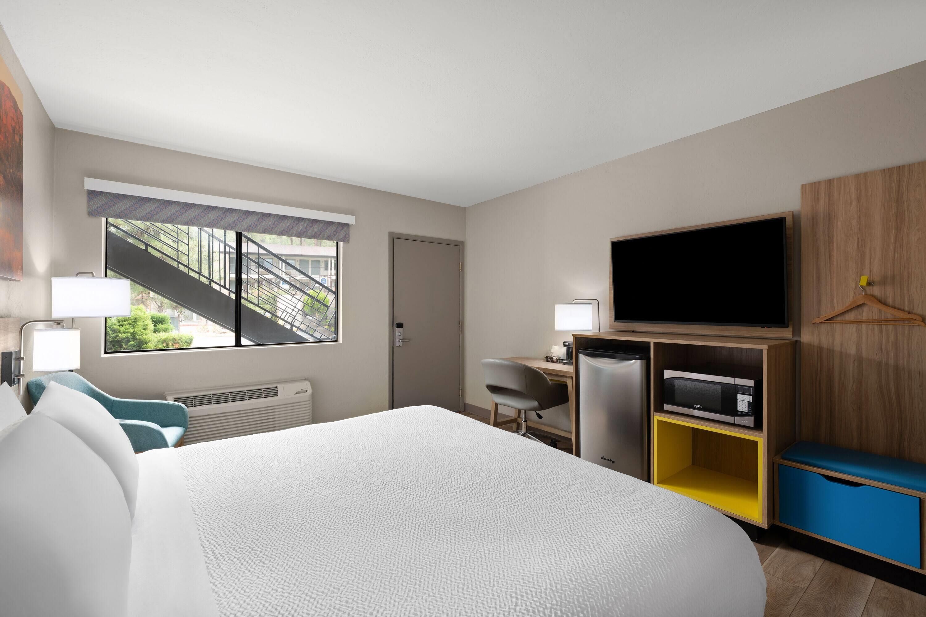 Habitación de hotel con cama, escritorio, televisor y vista a una escalera exterior.