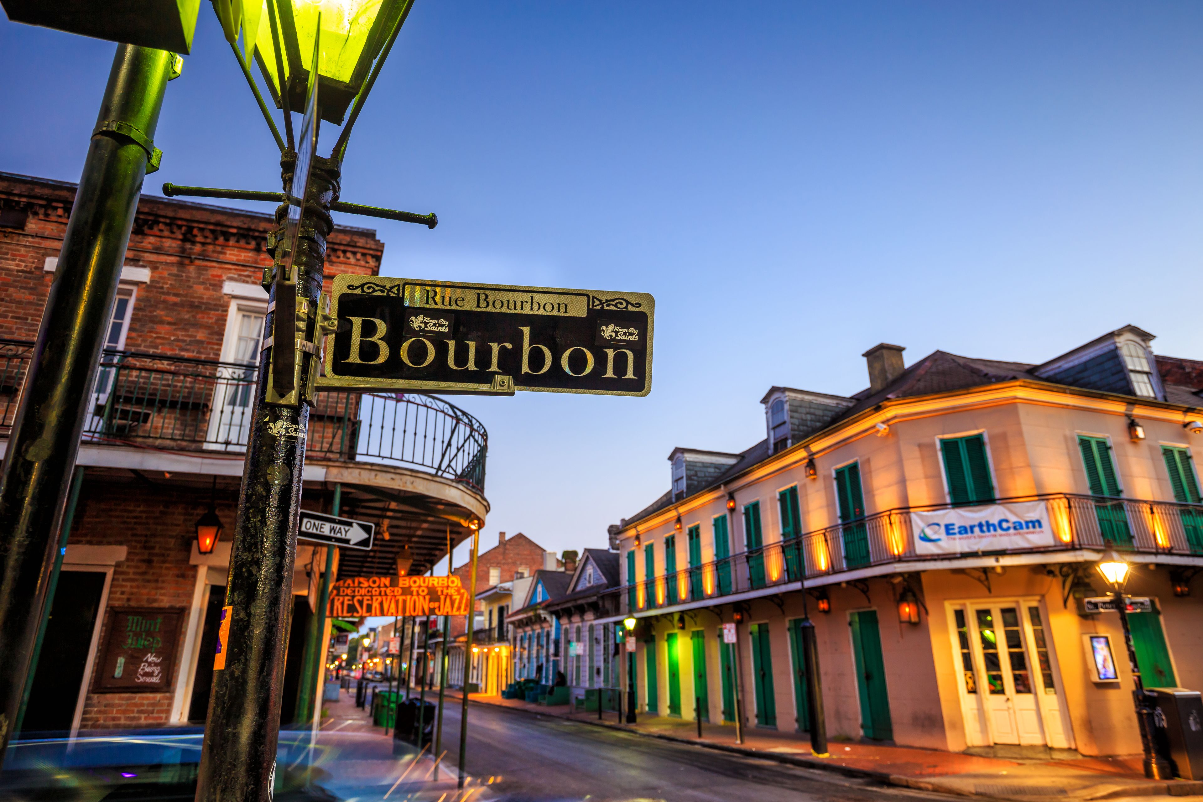 Una esquina de calle con un cartel de Bourbon Street, una señal de vía de un solo sentido y un edificio con un letrero de EarthCam.