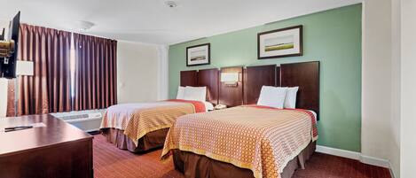 Habitación de hotel con dos camas, un escritorio y un aire acondicionado.