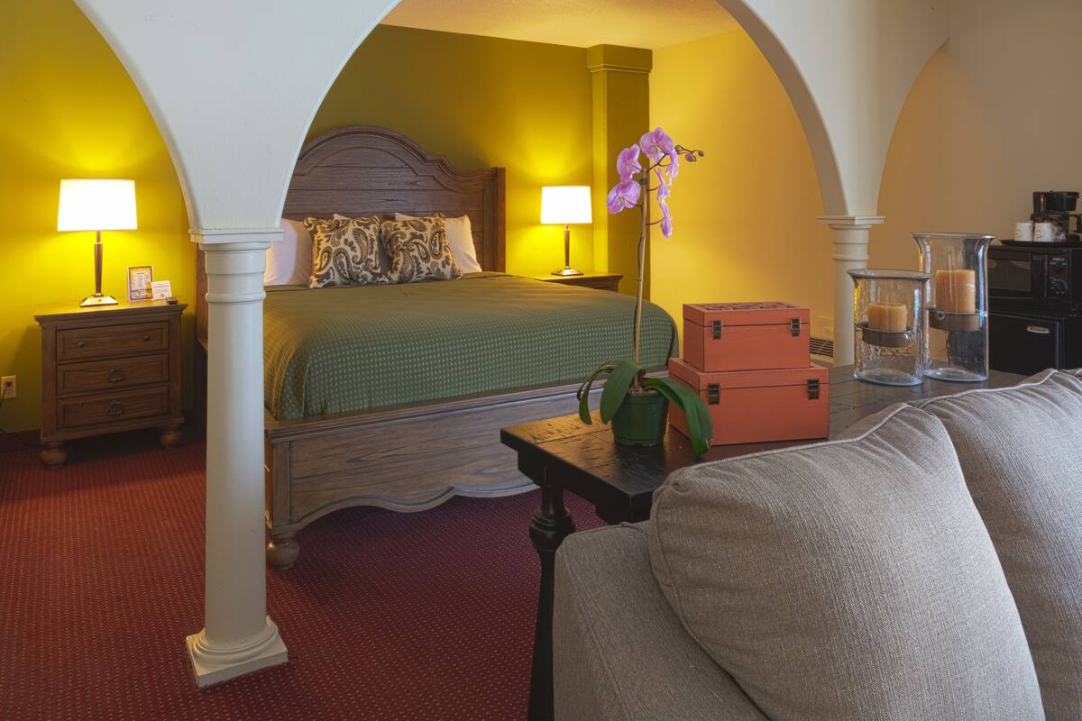 Une chambre à coucher comprenant un lit, deux tables de chevet, une petite table, une plante en pot et une commode.