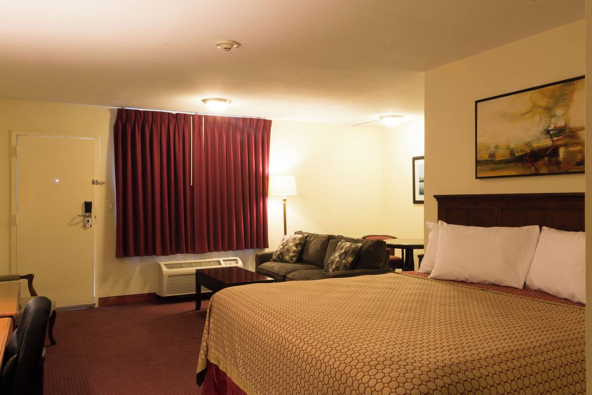 Une chambre d’hôtel avec un grand lit, un canapé, un bureau et une lampe.
