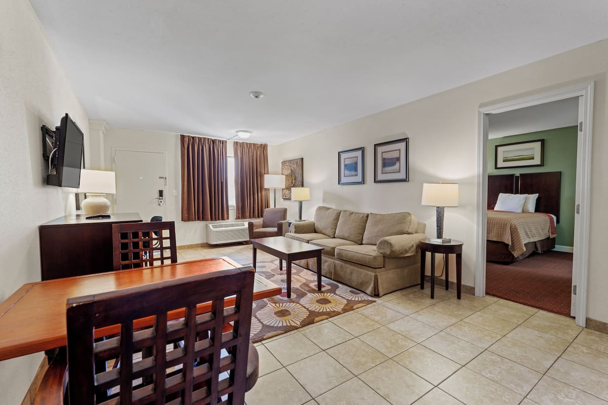 Une chambre d’hôtel comprenant un coin repas, un canapé, un lit et une télévision.