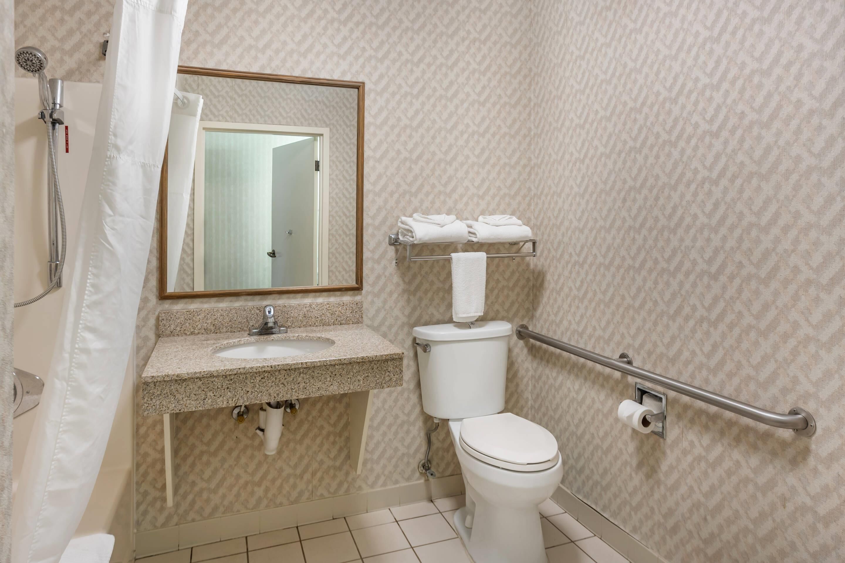 Un baño con lavamanos, inodoro y espejo.