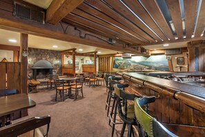 Un restaurante acogedor con muebles de madera, una chimenea de piedra y un mural en la pared.