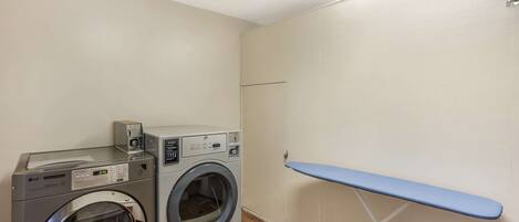 A laundry area with two washing machines and a drying rack.