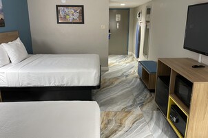 Habitación de hotel con una cama, televisor, escritorio con computadora y baño a la vista.