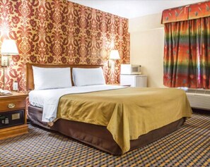 Classic hotel room with a large bed, nightstand, and patterned wallpaper.