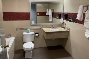 A bathroom with a toilet, sink, and mirror. - Days Inn by Wyndham Jersey City / NYC Area (Jersey City)
