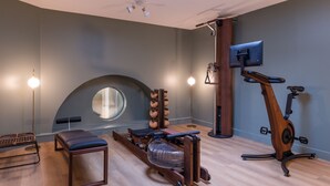 A modern room with a skylight, exercise equipment, a massage chair, and a massage table. - Leonardo Boutique Hotel Paris Opera (Paris)