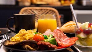 A breakfast setting with scrambled eggs, tomatoes, greens, and a glass of orange juice. - Leonardo Boutique Hotel Paris Opera (Paris)