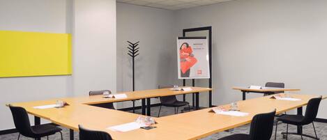 A conference room with long tables, black chairs, and a yellow accent wall.