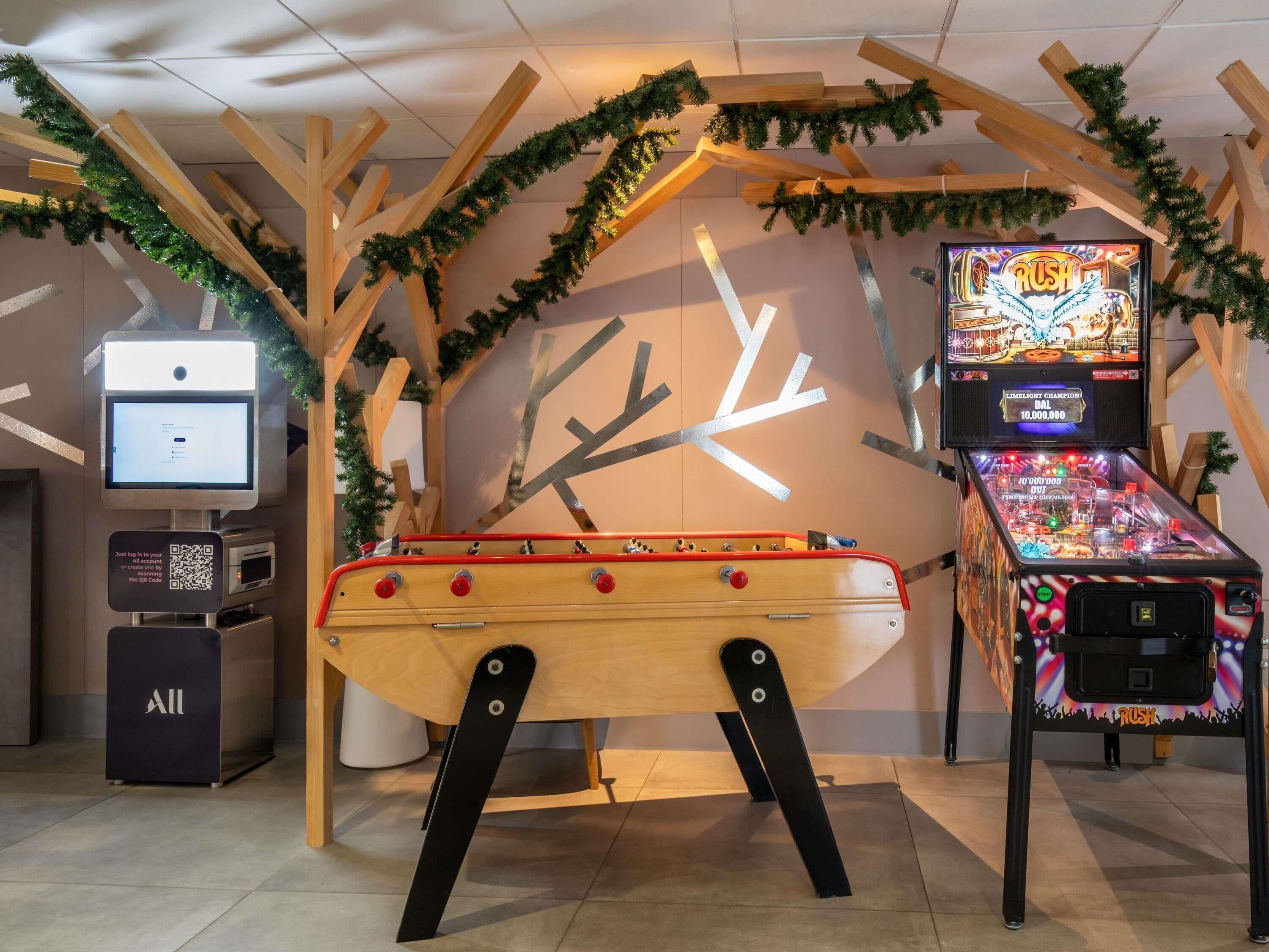 Eine Flippermaschine, ein digitaler Kiosk und eine Holzkonstruktion mit einer Design, das an eine Uhr erinnert.