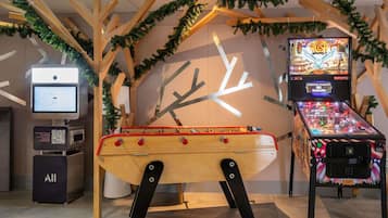 Eine Flippermaschine, ein digitaler Kiosk und eine Holzkonstruktion mit einer Design, das an eine Uhr erinnert.