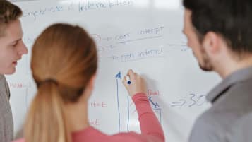 A whiteboard with diagrams and text, including 'Ergebnisse & Interaktion' and 'Qual.'