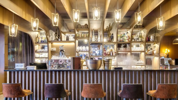 A bar area with multiple stools, shelves with bottles, and a counter with a large bowl. - ibis Paris Tour Eiffel Cambronne 15ème (Paris)