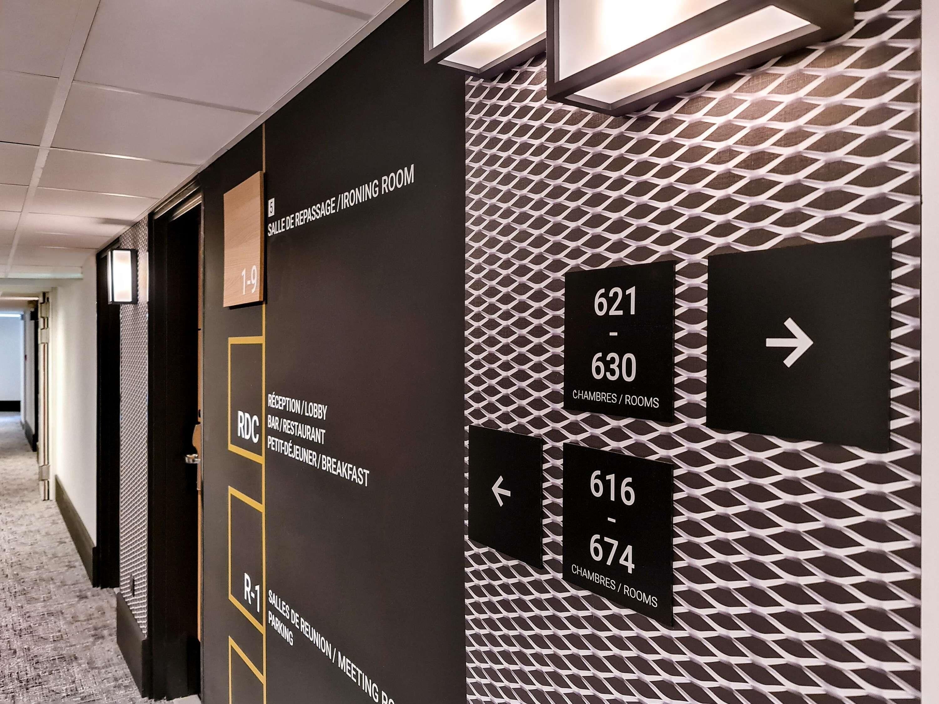 Een hotelgangen met borden die naar kamers en faciliteiten wijzen.