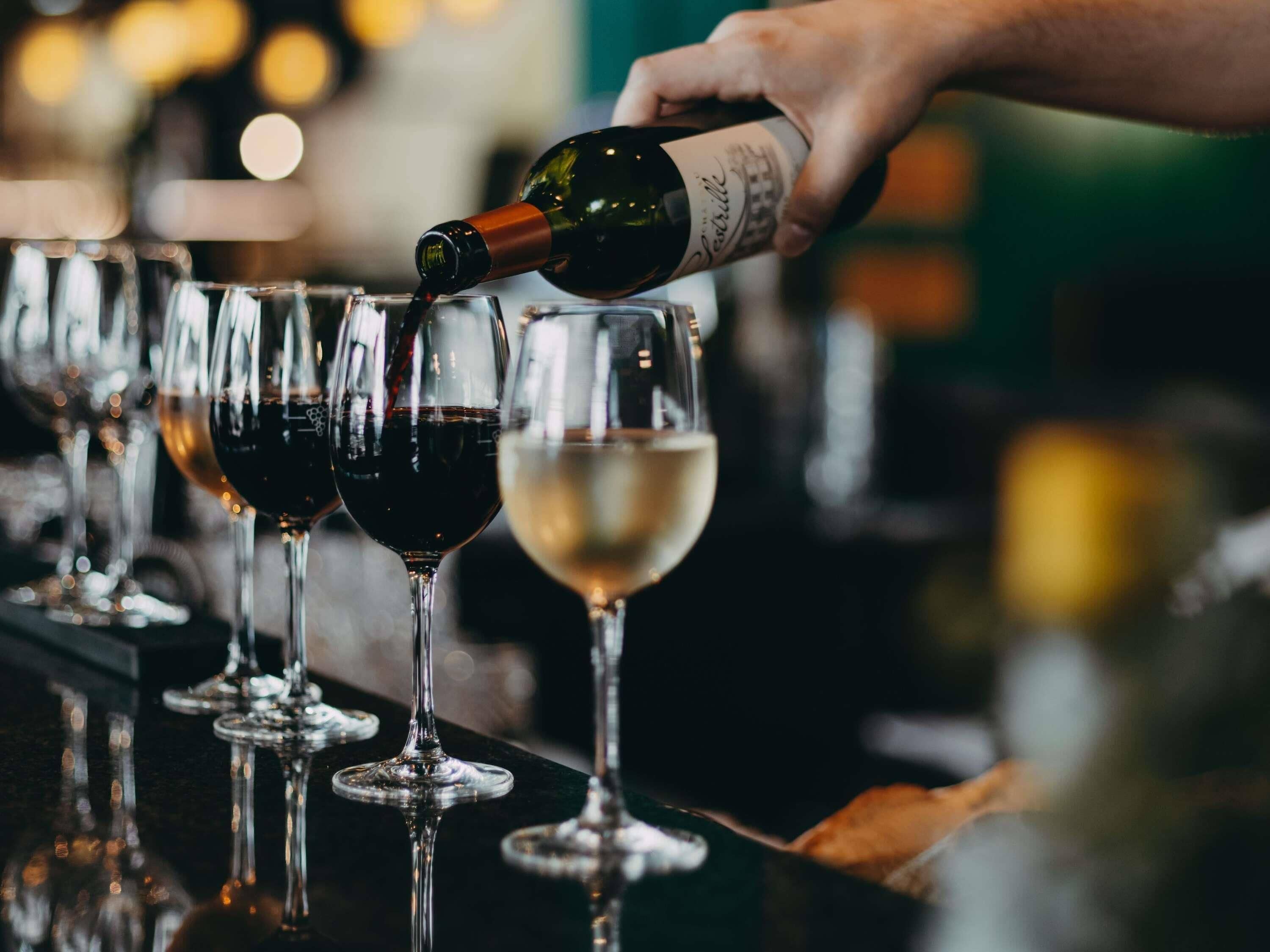 A hand pouring wine into a glass.
