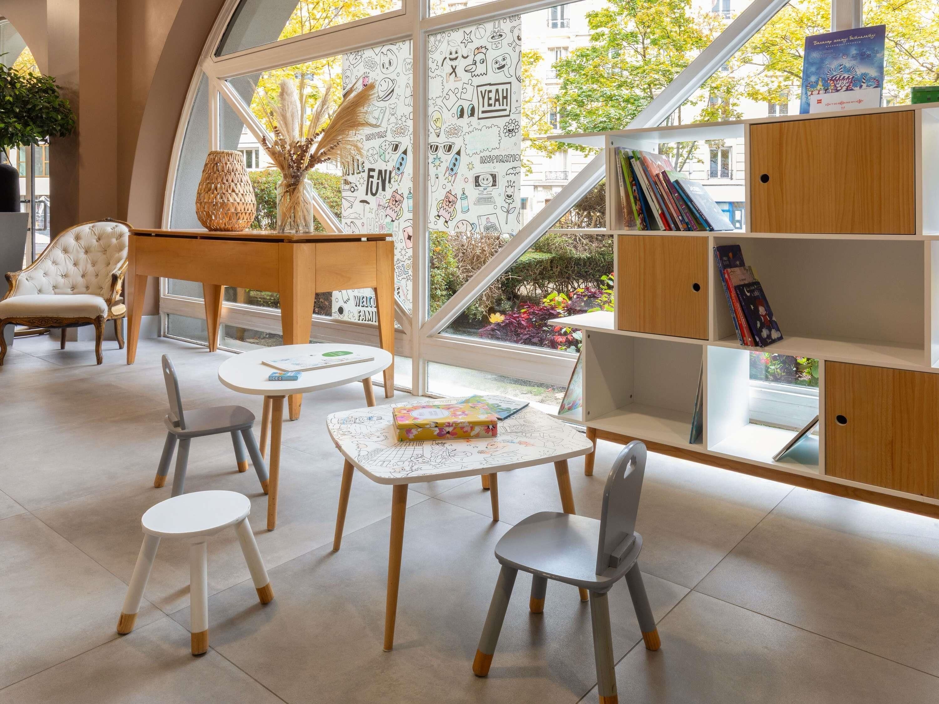 A modern library with a curved glass wall, wooden furniture, and a variety of books and decorative items.