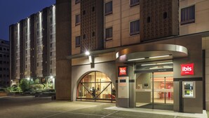 A modern hotel entrance with a glass facade, an escalator, and a digital display. - ibis Paris Tour Eiffel Cambronne 15ème (Paris)