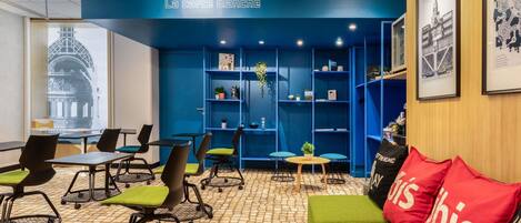 A modern interior with a blue accent wall, a green sofa, and a table with chairs.