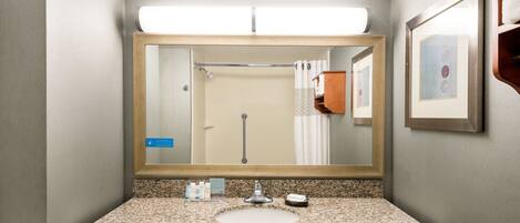 A bathroom with a granite countertop, a sink, a mirror, and a shower curtain.