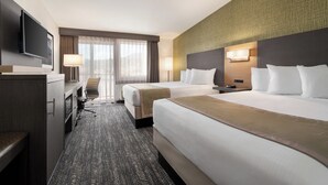 A hotel room with two beds, a desk, a TV, and a large window with curtains. - The Kendrick Hotel, an Ascend Collection Hotel (Flagstaff)