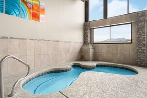 A spa area with a hot tub, a window with a mountain view, and a colorful abstract painting on the wall.