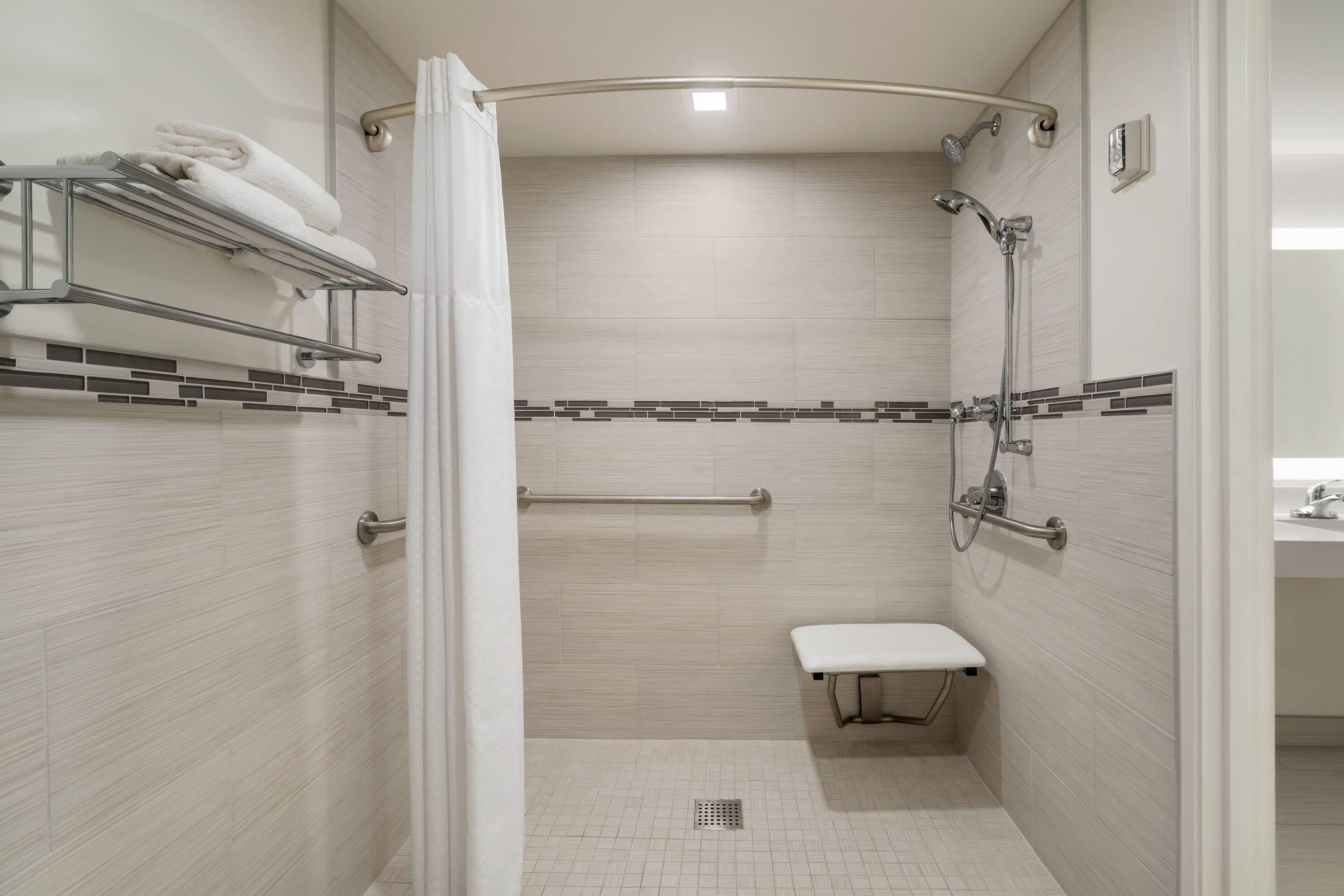 Un baño moderno con ducha, un banco, un perchero y una barandilla.