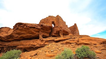 A large, reddish rock formation with a prominent cave-like structure.