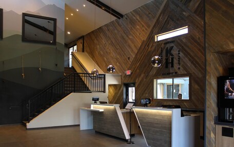 A modern reception area with a wooden wall, a reception desk, a staircase, and a television screen.