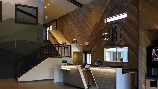 A modern reception area with a wooden wall, a reception desk, a staircase, and a television screen. - The Kendrick Hotel, an Ascend Collection Hotel (Flagstaff)