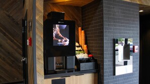 A modern kitchen with a built-in oven, a television mounted on the wall, and a brick wall. - The Kendrick Hotel, an Ascend Collection Hotel (Flagstaff)