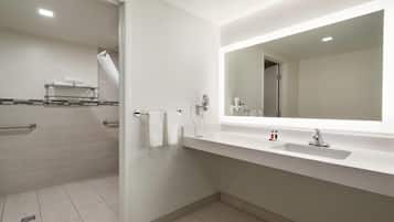 A modern bathroom with a white sink, a large mirror, and a shower area.