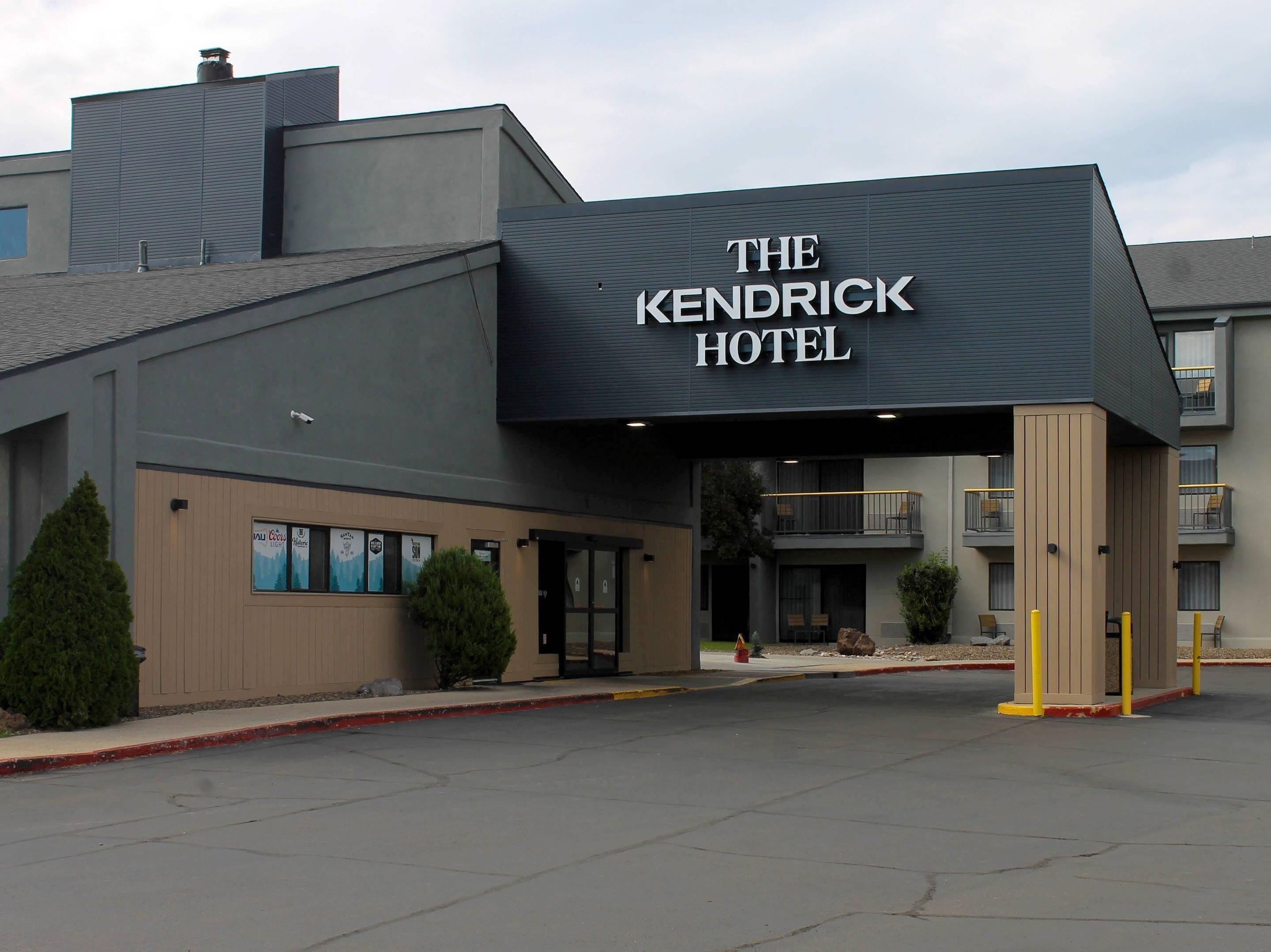The exterior of The Kendrick Hotel with a modern design, featuring a prominent entrance and a covered area with seating.