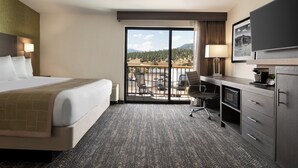 A hotel room with a bed, desk, and a view of a parking lot and mountains. - The Kendrick Hotel, an Ascend Collection Hotel (Flagstaff)