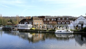 A riverside view of a town with historic buildings, a boat docked at the pier, and a white building labeled "The Compleat Angler". - Macdonald Compleat Angler (Marlow)