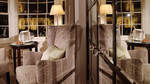A room with a view of a cathedral through large windows, a fireplace, and a table with a bottle of champagne and glasses. - Macdonald Compleat Angler (Marlow)