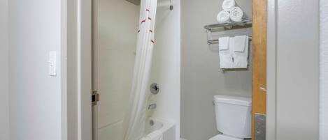 A bathroom with a shower curtain, a toilet, and a shelf with towels.