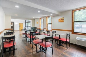 A dining area with multiple tables and chairs, a large window with a view, and a ceiling with recessed lighting.