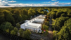 Un edificio con techo plano, rodeado de abundante vegetación y una masa de agua al fondo.