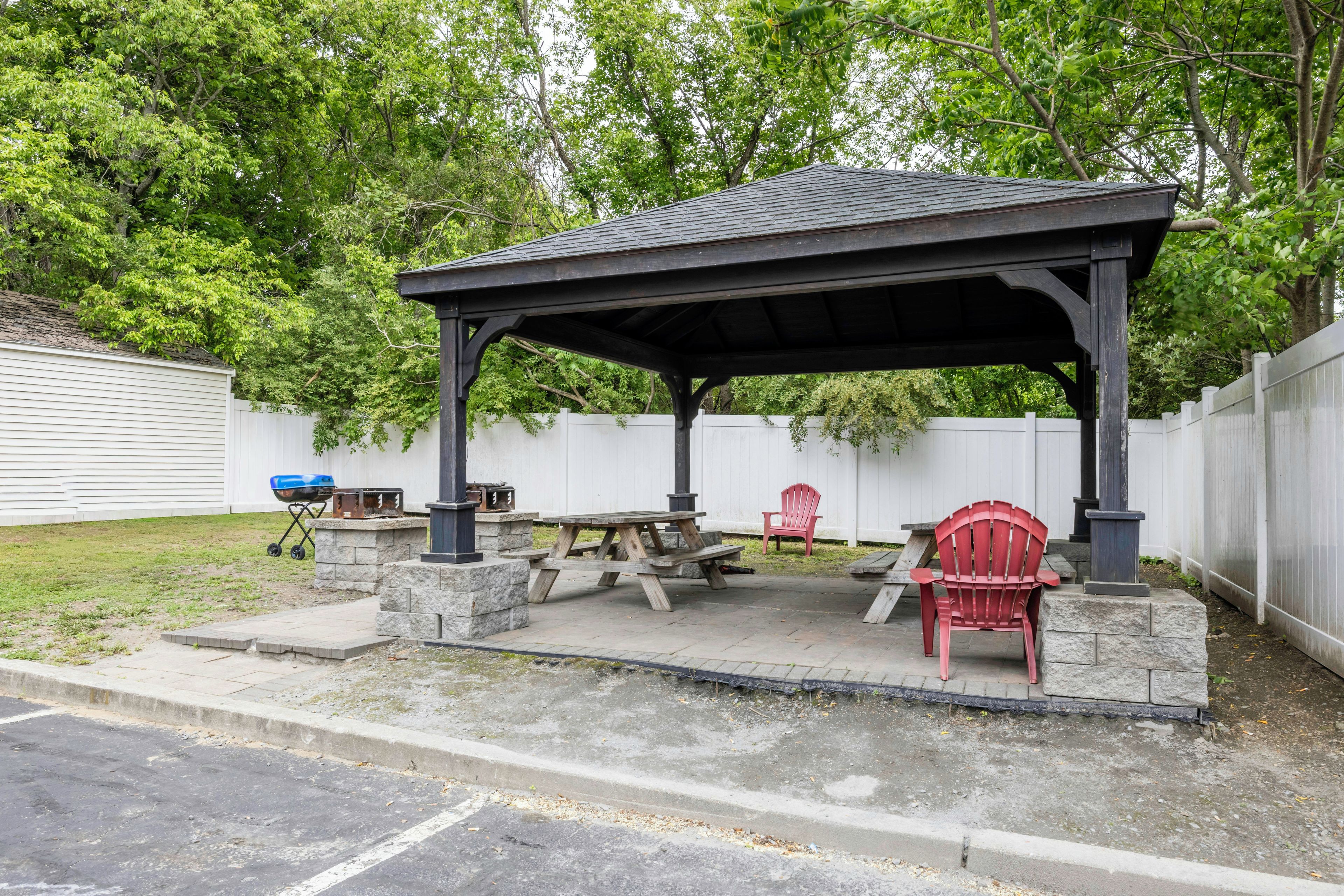 Un espace extérieur abrité, doté d’une table de pique-nique et de chaises, d’un barbecue et d’une base en pierre.