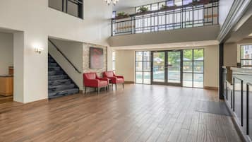 A spacious interior with a staircase, red chairs, and a view of the outdoors through large windows.