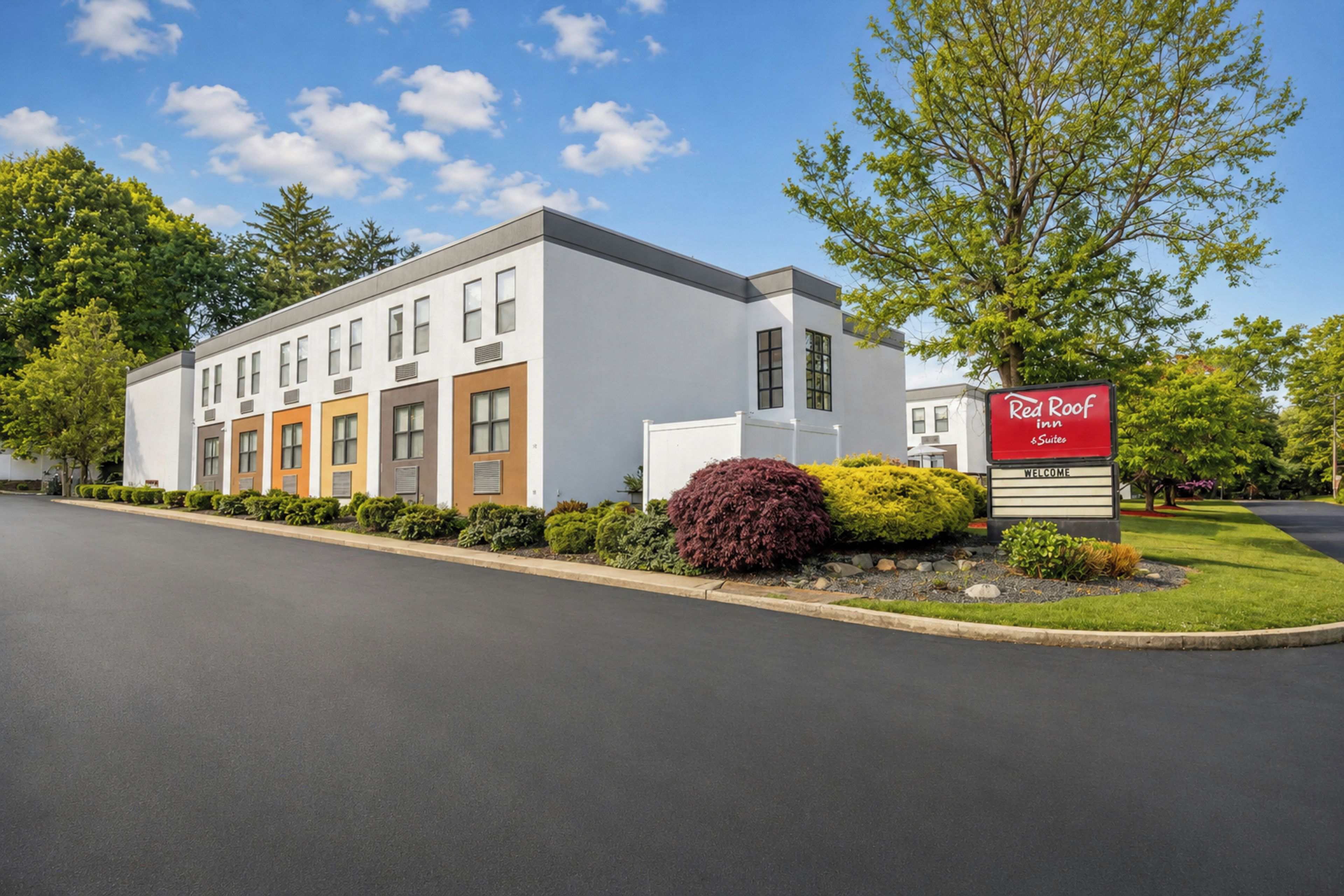 A Red Roof Inn with a modern building facade, a welcoming sign, and well-maintained landscaping.