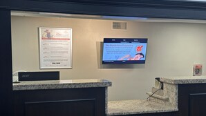 A reception desk area with a monitor displaying a message about a hassle-free guarantee. - Red Roof Inn & Suites Middleborough (Middleborough)