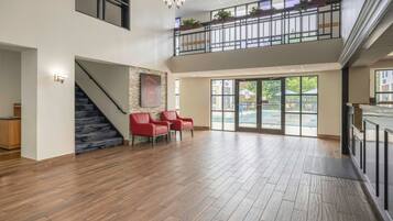 A spacious interior with a staircase, red chairs, and a view of the outdoors through large windows.