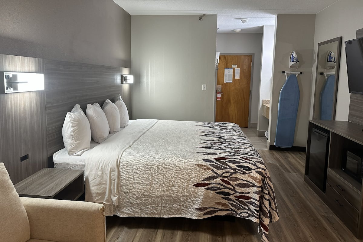 Habitación de hotel con cama, mesitas de noche, una silla, televisor y armario.