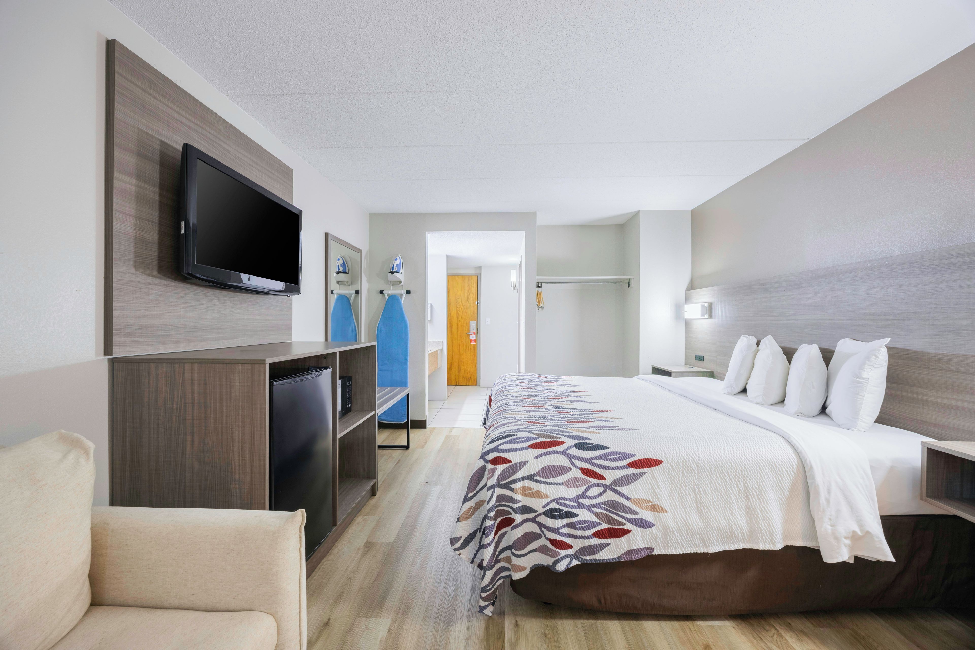 A hotel room with a bed, a television, a desk, and a chair.